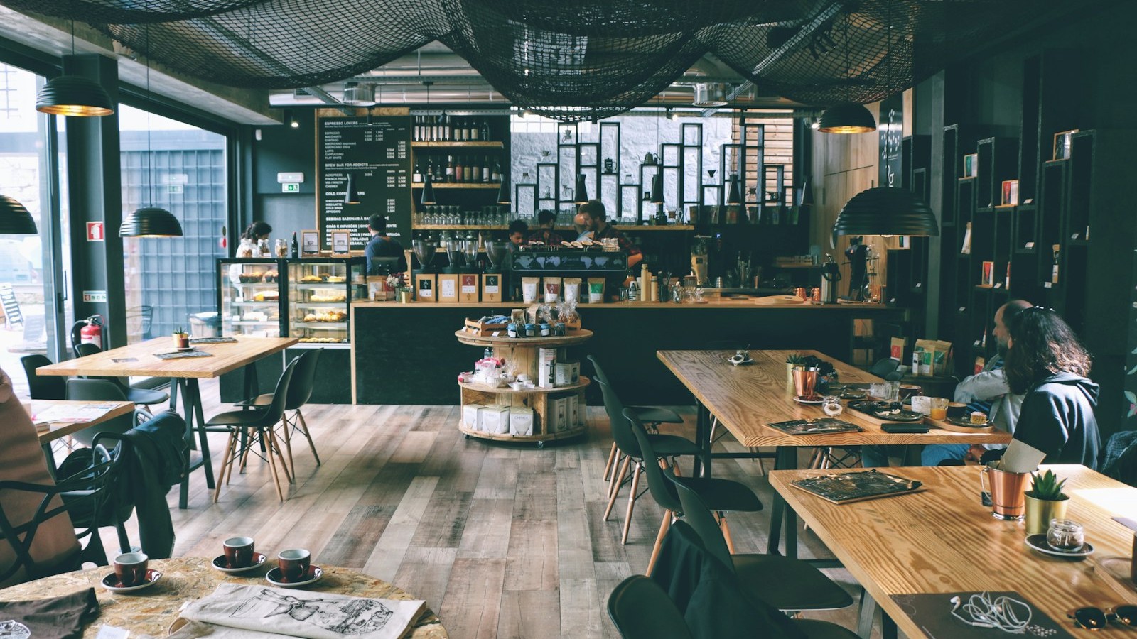 Bright spacious café with wooden tables and bar, natural light, remote-work vibe