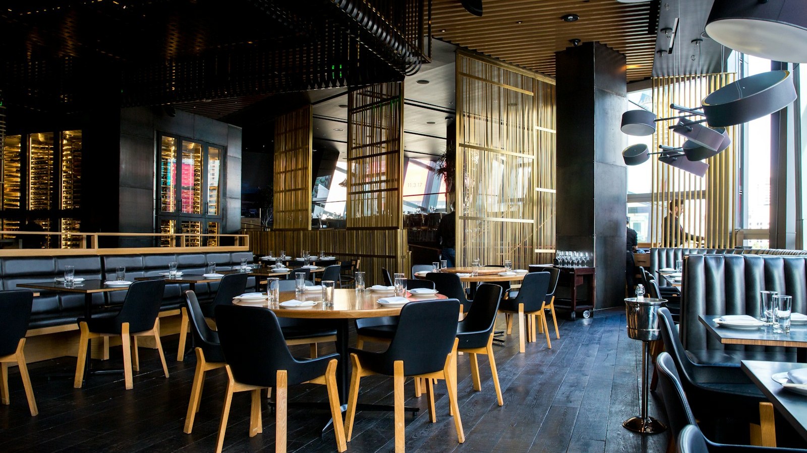 Wooden tables and chairs by a sunlit window, quiet city dining space